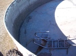An abandoned swimming pool on ranch land near the oil well.